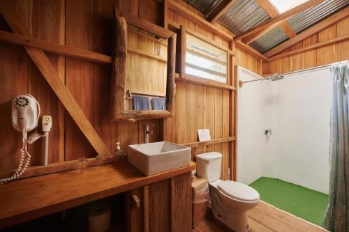 baño de madera con aseo y lavamanos en Finca Amistad Cacao Lodge en Bijagua