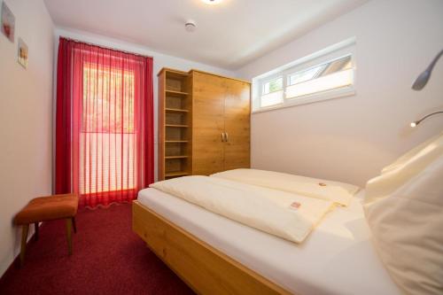 ヴァイセンゼーにあるFerienwohnungen Mittererのベッドルーム1室(ベッド1台、赤い窓付)