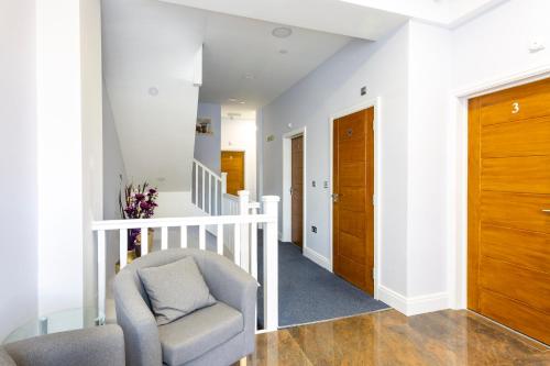 a living room with a chair and a staircase at Wellesley Hotel in Ilford