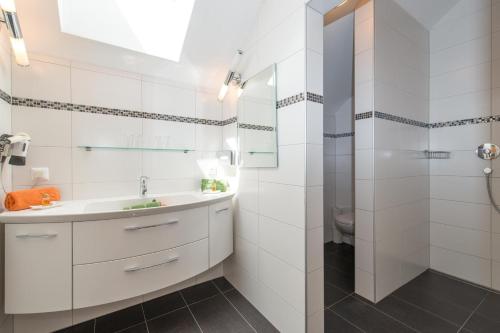 a white bathroom with a sink and a shower at Ferienwohnungen Mitterer in Weissensee