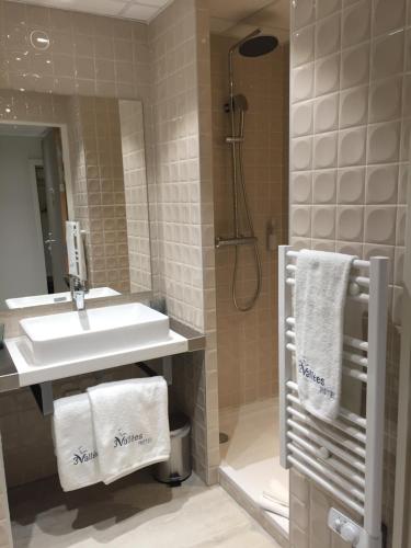 a bathroom with a sink and a shower and towels at HOTEL LES 3 VALLÉES in Saran