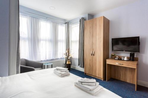 a hotel room with a bed with a television and a cabinet at Wellesley Hotel in Ilford