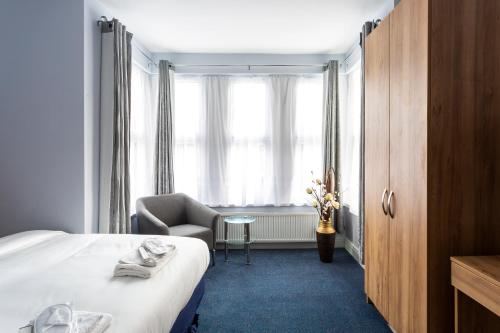 a hotel room with a bed and a chair and a window at Wellesley Hotel in Ilford