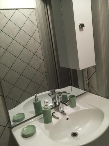 a bathroom sink with a mirror and green cups on it at Pretoria House in Potenza