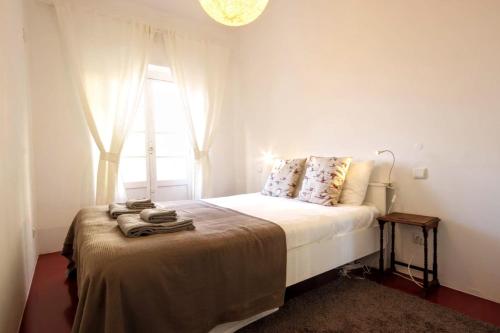 a white bedroom with a bed with a window at Belém Calling Apartment in Lisbon