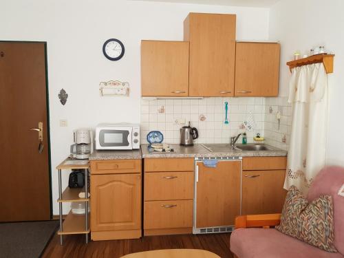 una pequeña cocina con armarios de madera y microondas en Haus Rita, en Mittenwald