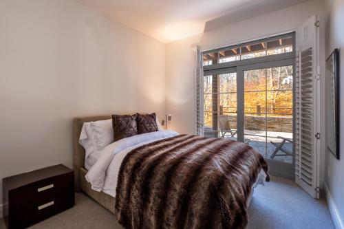um quarto com uma cama e uma grande janela em Tremblant Prestige-Panache 506 em Mont-Tremblant