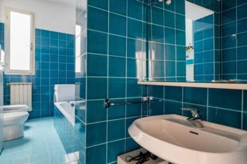 ボローニャにあるwhouse suite porta di castelloの青いタイル張りのバスルーム(洗面台、トイレ付)