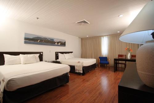 a hotel room with two beds and a desk at Hotel CCT Caracas in Caracas