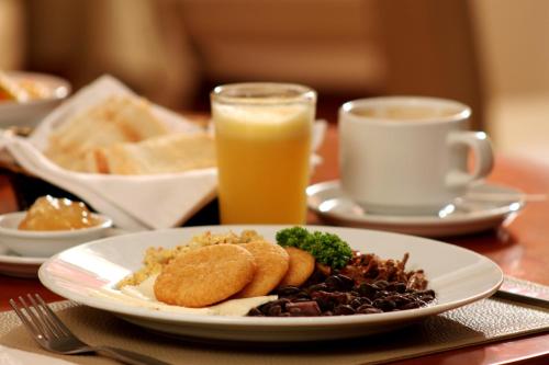 a plate of food on a table with a glass of orange juice at Hotel CCT Caracas in Caracas