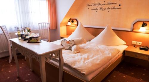 een slaapkamer met een bed en een tafel met een lamp bij Hotel Birkenhof Garni in Baabe