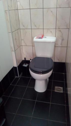 a bathroom with a white toilet with a black seat at Comfy Apartment near the Sea in Ierápetra