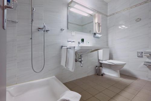 ein Badezimmer mit einer Badewanne, einem Waschbecken und einem WC in der Unterkunft Hôtel Crystal in Lausanne