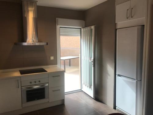 a kitchen with a refrigerator and a door to a patio at Fercamar Costacabana in Almería