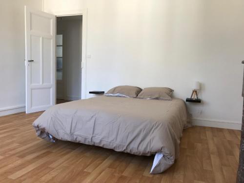 洛里昂的住宿－Lesage 2，铺有木地板的白色卧室内的一张床位