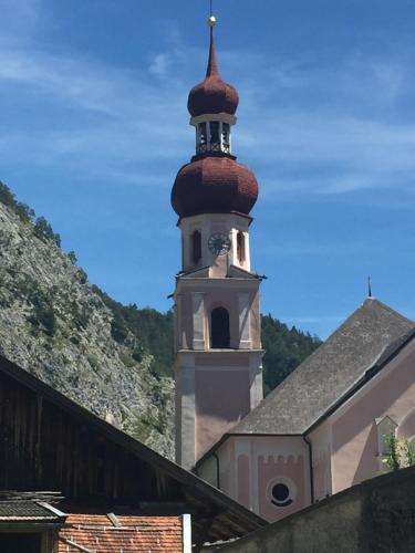 a building with a tower with a clock on it at Chalet am See in Nassereith