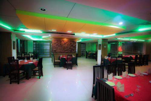 a dining room with tables and chairs and green lights at Hotel 71 in Dhaka