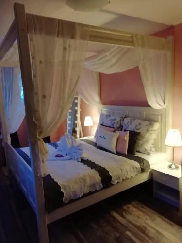 a bedroom with a canopy bed with white sheets and pillows at Penzion Blatno in Blatno