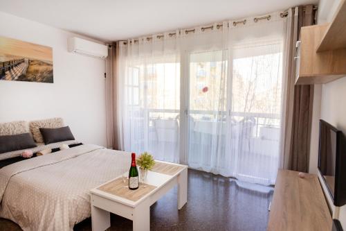 Un dormitorio con una cama y una mesa con una botella de vino en Anne, en Salou