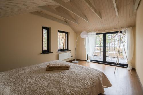 - une chambre avec un lit dans une pièce dotée de fenêtres dans l'établissement Jūras Krasti Romantika, à Jūrmalciems