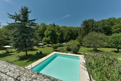 a swimming pool in a garden with trees and grass at Le Prieuré L´Atelier in Lanzac