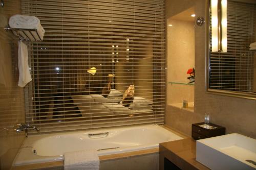 a bathroom with a tub and a window and a sink at Ritan Hotel Downtown Beijing in Beijing