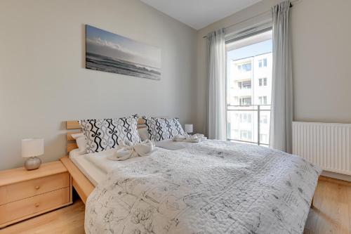 a white bedroom with a bed with a window at Wave Apartments Nowa Grobla Old Town in Gdańsk