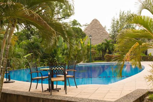 a table and chairs next to a swimming pool at Hotel Villa Mercedes Palenque in Palenque