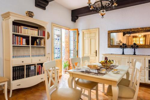 comedor con mesa, sillas y espejo en HSH Suites Barrio Santa Cruz, en Sevilla