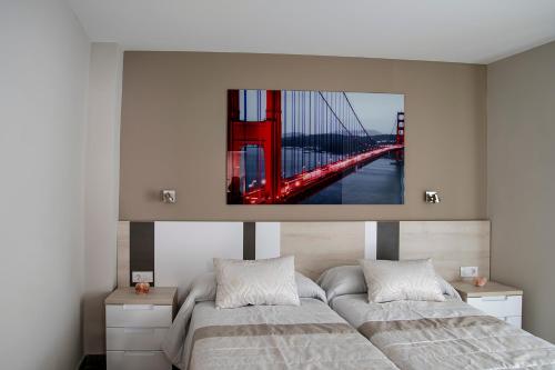 two beds in a bedroom with a bridge painting on the wall at Alojamiento Turistico La Casa del tio Cesar in Cañas