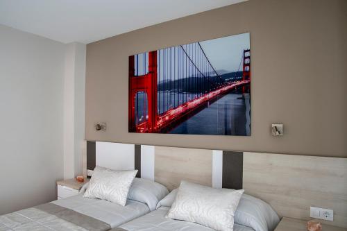 a painting of the golden gate bridge above a bed at Alojamiento Turistico La Casa del tio Cesar in Cañas