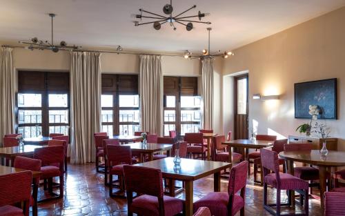 a dining room with tables and chairs and windows at Parador de Jarandilla de la Vera in Jarandilla de la Vera