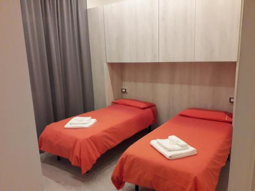 two beds in a room with red sheets and white towels at La CasaLina in Omegna