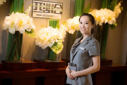 a woman standing in front of vases of flowers at Huachen International Hotel in Hangzhou