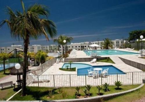 a swimming pool with a palm tree and a building at Marina Clube in São Pedro da Aldeia