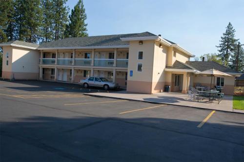 a building with a car parked in a parking lot at Shasta Pines Motel & Suites in Burney