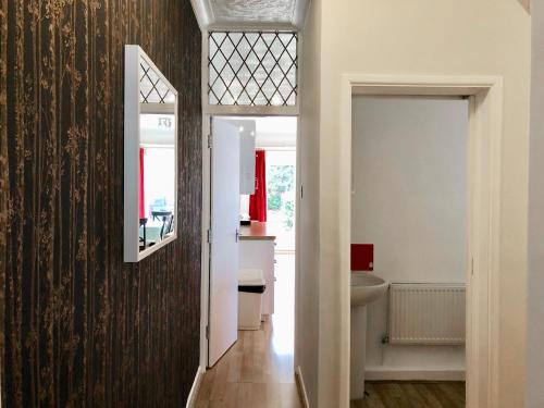 a hallway with a bathroom with a sink and a mirror at Little Connaught House in Portsmouth