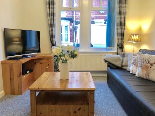 a living room with a couch and a table with flowers on it at Little Connaught 2 bed House pet friendly in Portsmouth