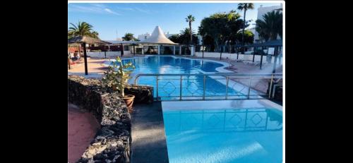 a pool at a resort with a building in the background at luxury casa playa roca bord de mer in Costa Teguise