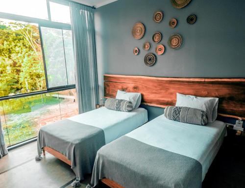 two beds in a room with a window at Enai in Puerto Maldonado