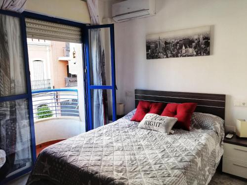 Un dormitorio con una cama con almohadas rojas y una ventana en Apartamento y Parking en pleno CENTRO, DAMAS en Huelva