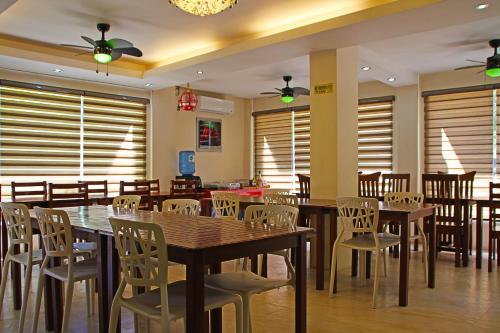 a dining room with tables and chairs and windows at Giecel Pension in El Nido
