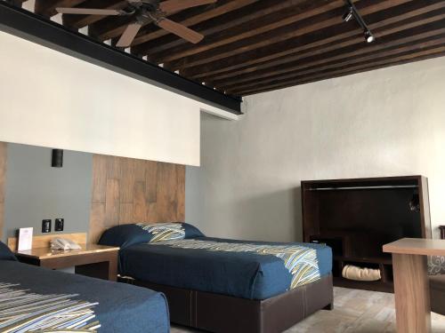 a bedroom with two beds and a flat screen tv at Hotel Frida in Puebla