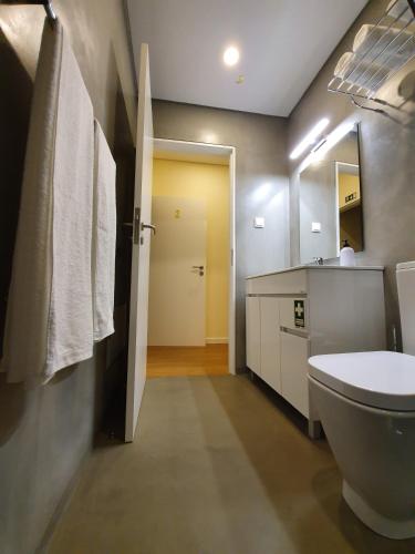 a bathroom with a toilet and a sink and a mirror at Agnelo Comfort - Accommodation H V in Funchal