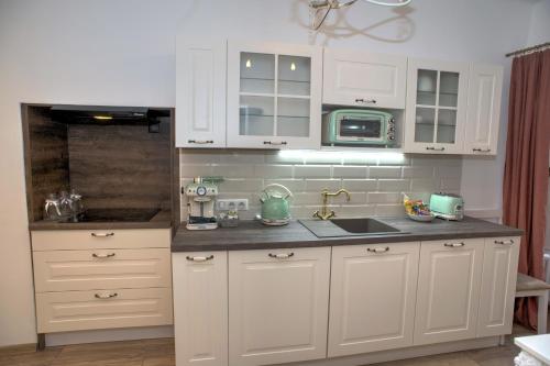 a kitchen with white cabinets and a sink and a microwave at Křišťanka - kouzelné apartmány in Prachatice