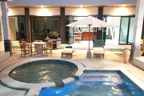 a pool with a table and chairs and an umbrella at Villa Viking in Jimbaran