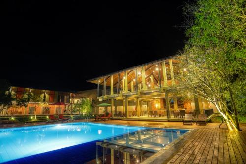 a swimming pool in front of a building at night at Tropical Life Resort and Spa in Dambulla