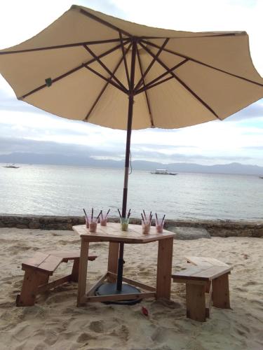a picnic table with an umbrella on the beach at Ancelle Cristo Re in Moalboal