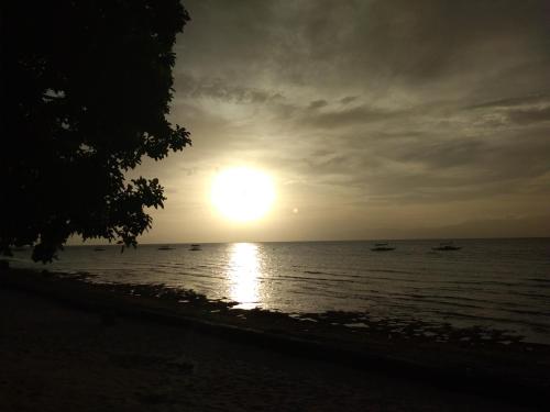 a sunset on the beach with boats in the water at Ancelle Cristo Re in Moalboal