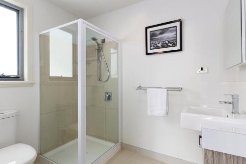 a white bathroom with a shower and a sink at 170 Hazards View Drive - Unit 2 in Coles Bay